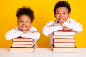 Photo of happy cheerful people young dark skin children sit desk book smile pupils isolated on yellow color background