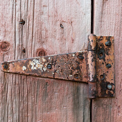 Rusty hinge on red barnwood