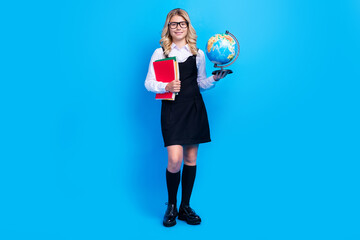 Full length photo of cheerful young charming girl hold hands globe notebooks smile isolated on blue color background
