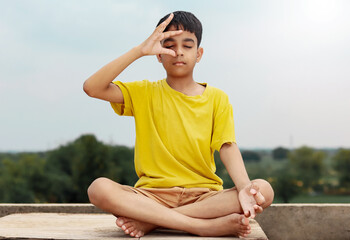 Fototapeta na wymiar A young indian cute kid doing yoga anulom vilom pose.