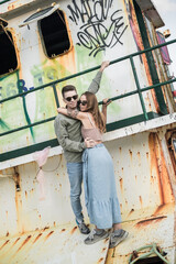 Fototapeta na wymiar Couple in love on the old pier. Wearing casual clothes, sunglasses, enjoying summer time. Millennial couple. High quality photo