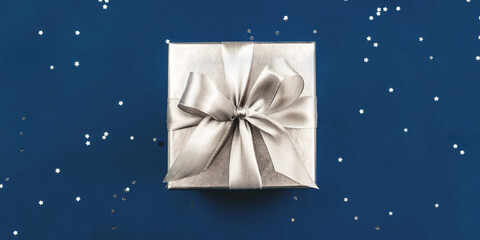 Silver gift box with bow on blue background.