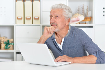 Fototapeta premium Emotional senior man using laptop