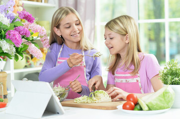 Two girls in pink aprons preparing salad