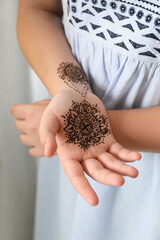 Little girl with henna tattoo on palm, closeup. Traditional mehndi ornament