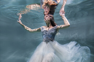 portrait of a model under water with highlights in a beautiful blue dress