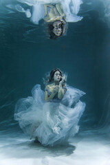 underwater photography. Girl mermaid. model in water in a beautiful dress swims like a fish.In a blue flying dress. 