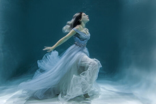 underwater photography. Girl angil. model in water in a beautiful dress swims like a fish.In a blue flying dress. 