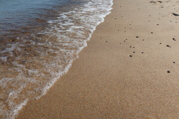 Soft blue sea wave on clean sandy beach. Abstract sand of beach and soft wave background