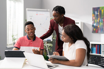 Two men and beautiful woman sit in an office in the morning, preparing for work, a conference, a training session, discussing strategy, talking about a project, browsing the internet for information