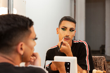 young drag queen artist doing her makeup in the dressing room