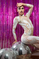 young drag queen with short hair and mustache posing with fuchsia color background