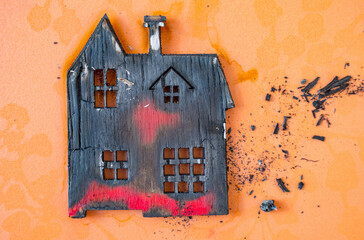 Home fire insurance concept. Miniature residential wooden building after fire.