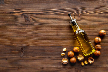 Obraz na płótnie Canvas Macadamia nut oil in glass bottle with nuts. Essence extra virgin oil for food or cosmetic