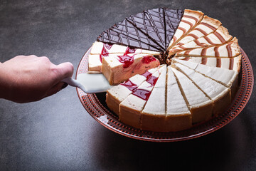 Obraz premium hand with the dessert spatula takes a piece of cheesecake