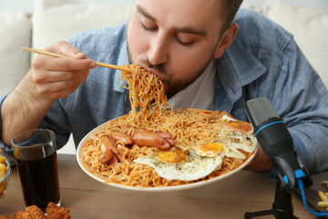 Food blogger eating in front of microphone at table, closeup. Mukbang vlog