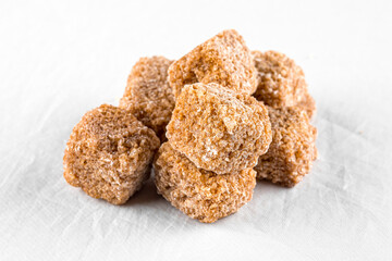 Isolated handful of brown cane sugar cubes on a white background