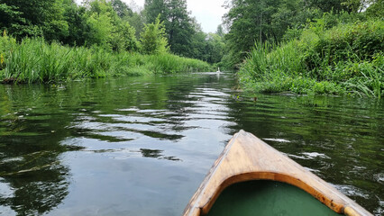 The wooden nose of a kayak on the background of a river in the middle of the forest. Extreme kayaking. Water sports, adrenaline, kayaking and adventure concepts..