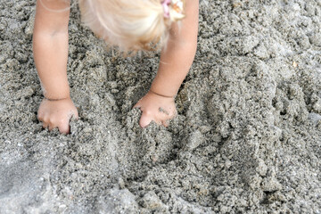 The child collects dirty sand in his hands.