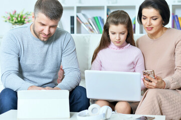 Happy parents and daughter using digital devices