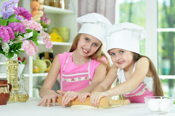 Obraz na płótnie Canvas Cute little girls in hats making dough