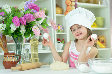Cute girl in chefs hat making dough