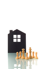 Chess pieces with silhouette of a house in the background.