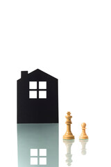 Chess pieces with silhouette of a house in the background.