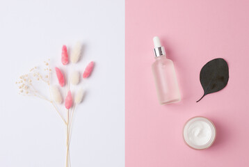 Minimal composition with cosmetic skin care products and flowers on pink background. Flat lay.