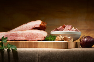 Pedaços de bacon de pernil, sobre tábua de corte de madeira.