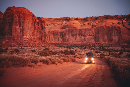 A car is on the road in the middle of the Monument Valley, Arizona, US