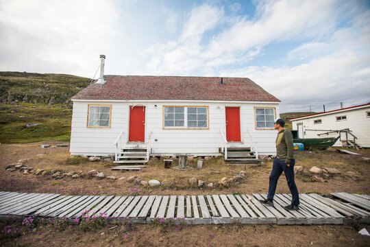 Man walks on boardwalk near historical Hudson Bay Company outpost.