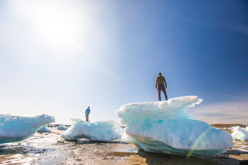Two men standing on sea ice chunks, Iqaluit, Canada.