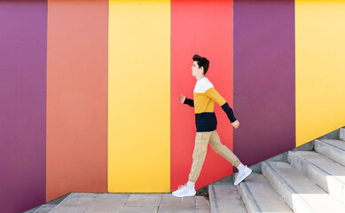 Adolescent going down stairs outdoor against colored wall