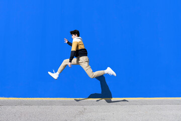 Young man jumping on the urban wall background