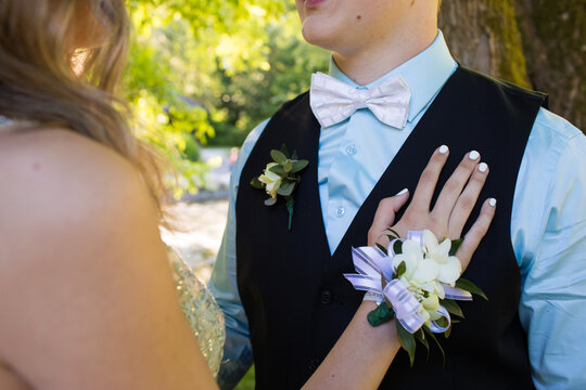 Young woman wearing corsage touches her partners chest