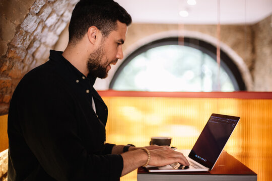 Concentrated man using laptop computer at cafe