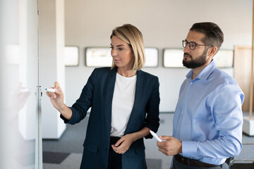 Colleagues drawing scheme on whiteboard