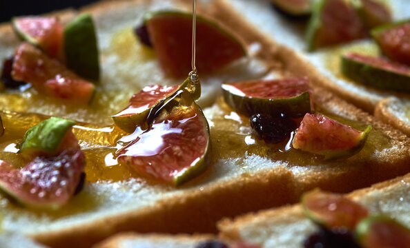 Close-up view pouring honey on the figs and bread