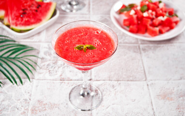 Watermelon refreshing summer frozen cocktail smoothie with watermelon slices and pieces on the background