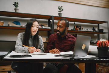 Female tailor and black man doing sketch for clothing in workshop