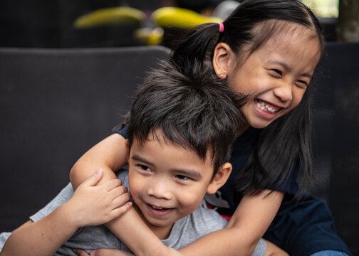 picture of two young Thai siblings playfully embrace