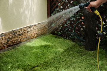 Man watering unrolled grass sods at backyard, closeup