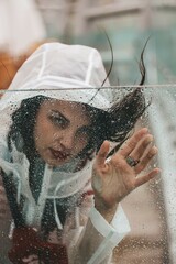 girl in the rain in a raincoat. Drops on glass.