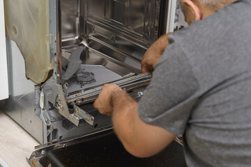 a man removes a damaged, dirty rubber seal for replacement. dishwasher repair