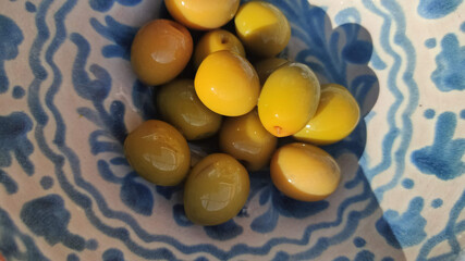 Green olives on (Fajalauza) traditional ceramic from Granada, Spain. Top view with sun ray