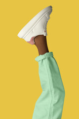 Woman wearing sneakers on yellow background, closeup