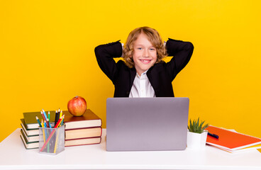 Photo of relaxed schoolkid sit desk enjoy comfy break rest wear uniform isolated yellow color...