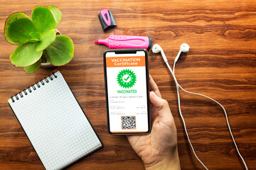 hand woman holding a mobile phone with digital vaccination certificate to certify that have been...