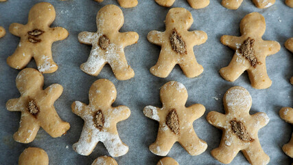 cookies made of cottage cheese and rice flour with date syrup on parchment paper in the form of a gingerbread man sprinkled with cinnamon and sugar, prepared at home. top view
